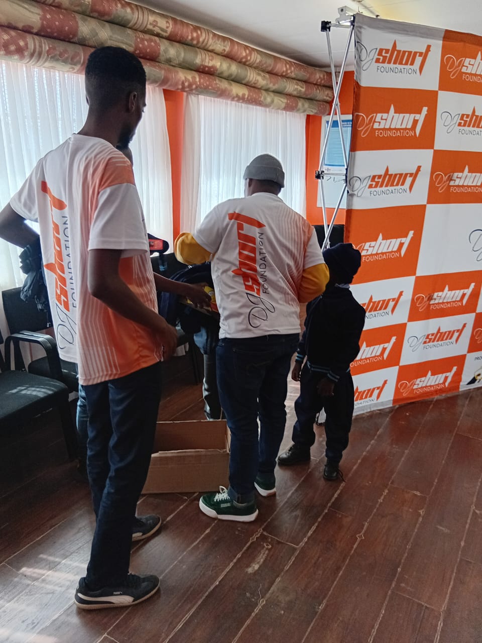 Volunteers assisting a learner to try on the new school uniform