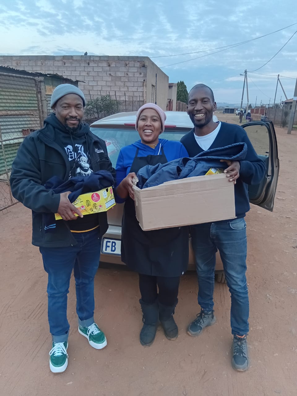 A parent receiving a school uniform and shoes for her child from DJ Short Foundation