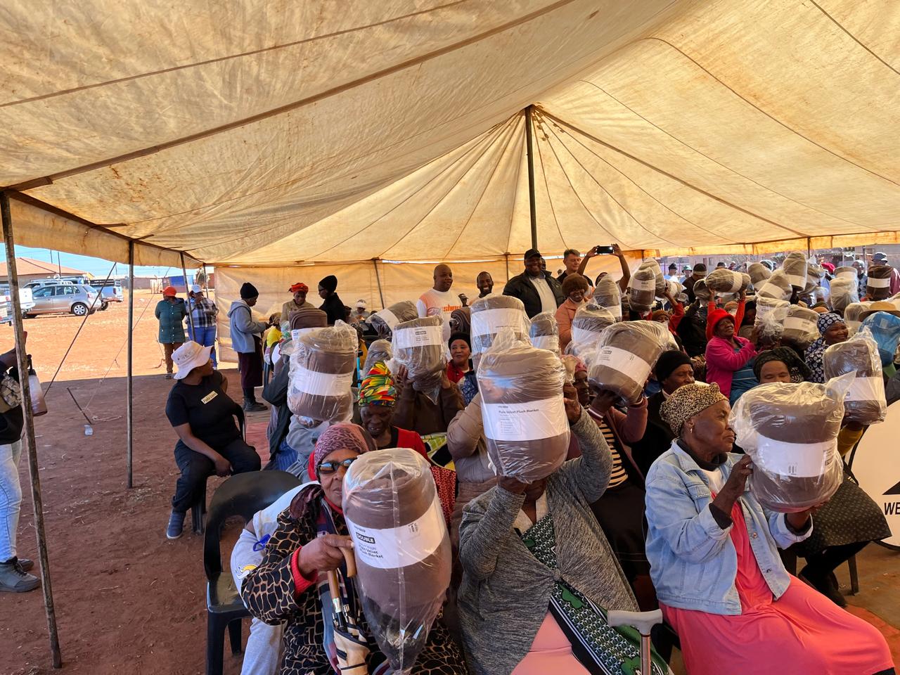 Elderly guests displaying blankets received at the community initiative